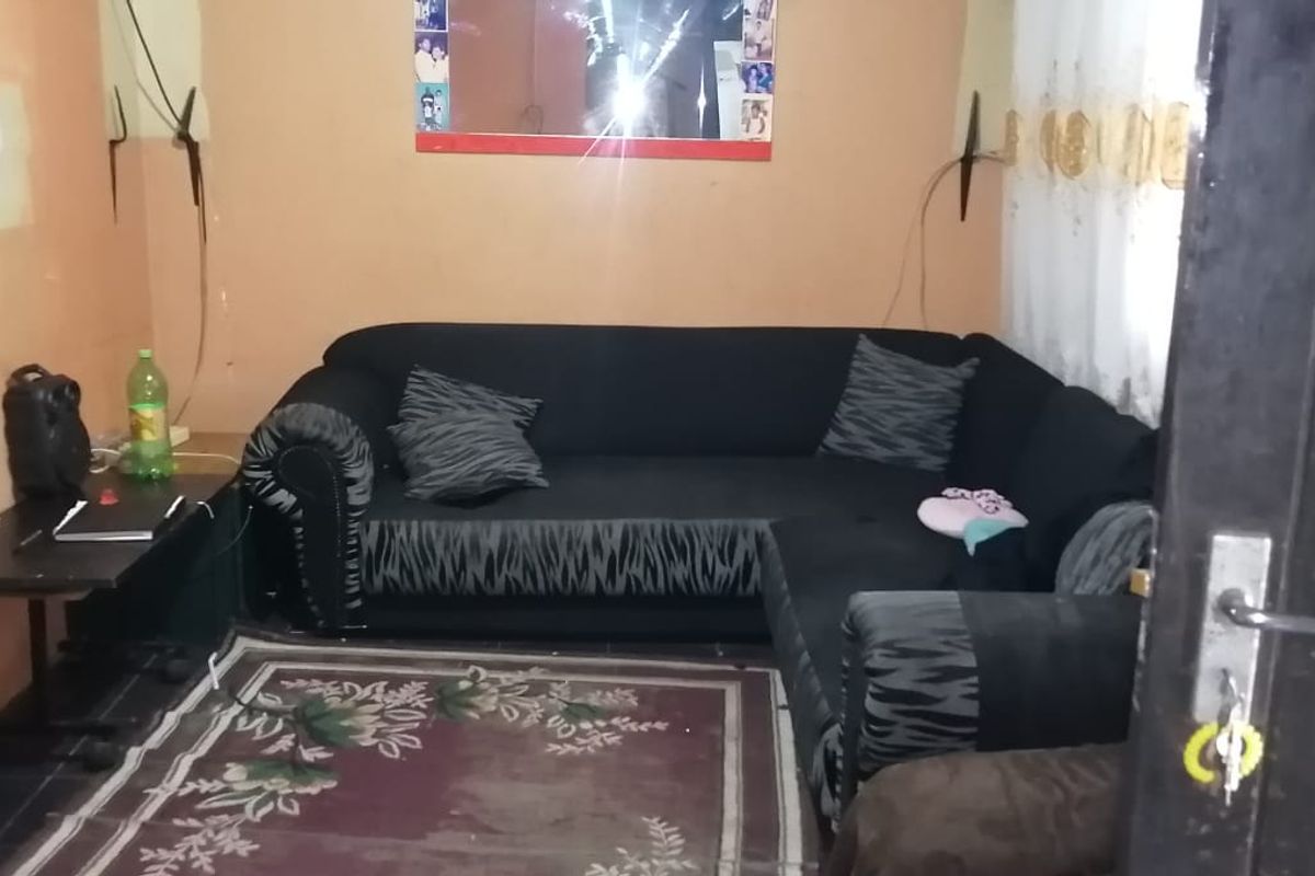 A living room space featuring tiled flooring and walls requiring cosmetic attention and repainting.