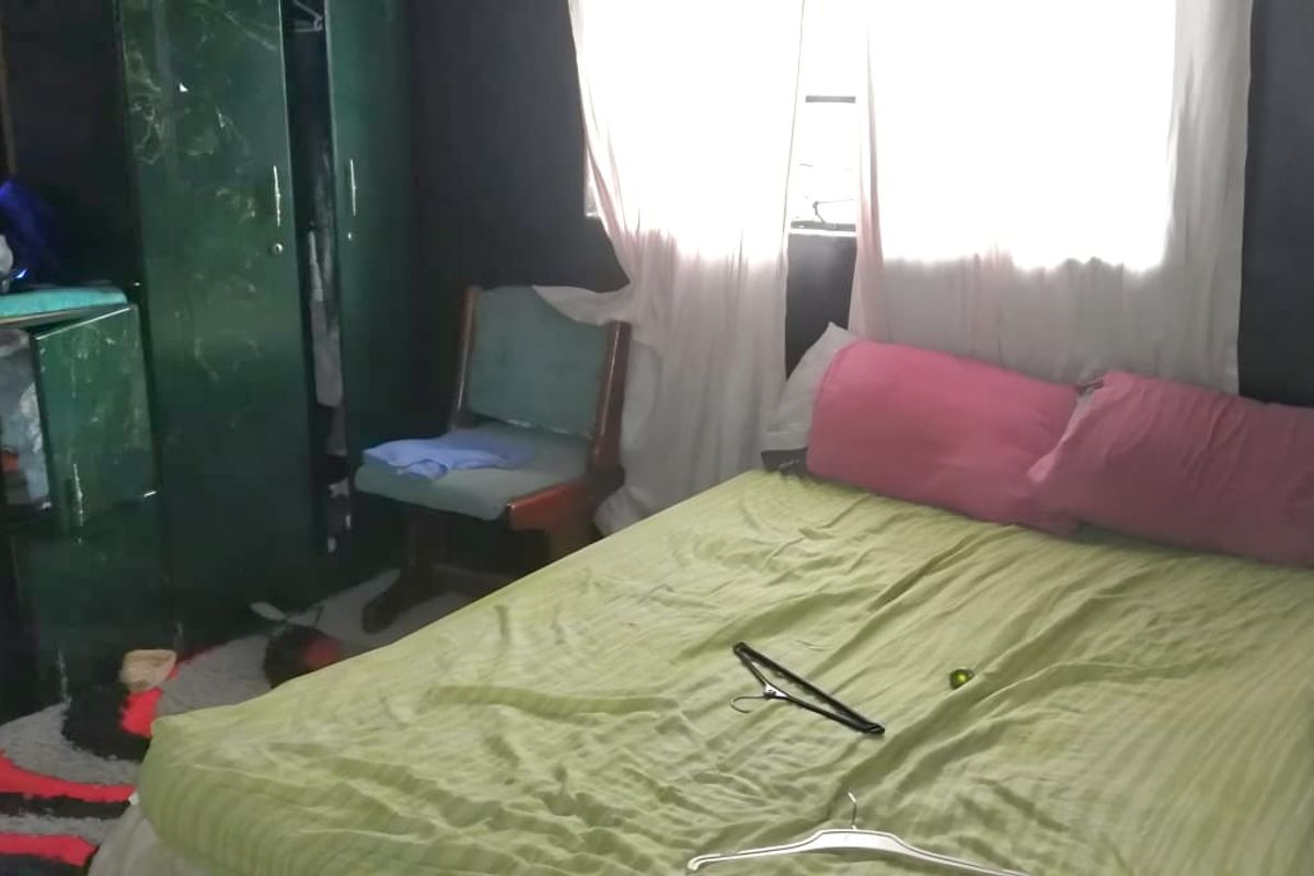 A bedroom featuring dark walls and a window with curtains.