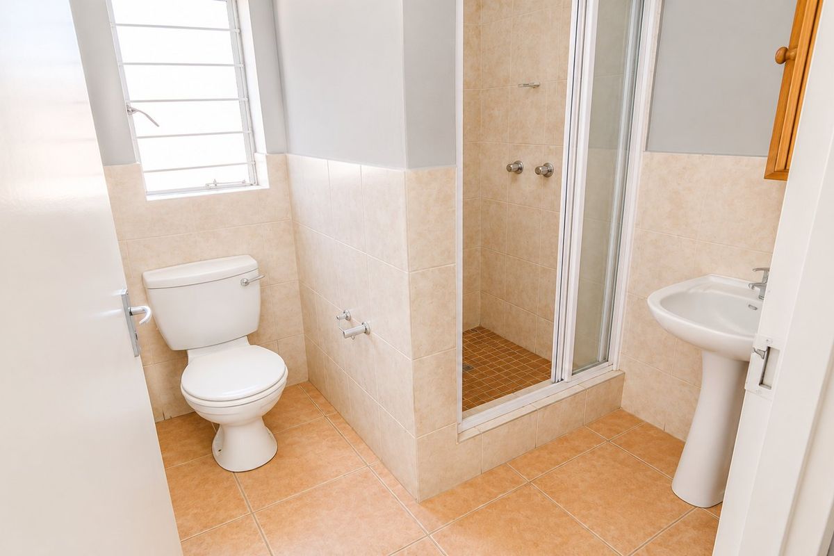A functional bathroom featuring a pedestal basin, toilet, and a separate shower enclosure with tiled finishes throughout.