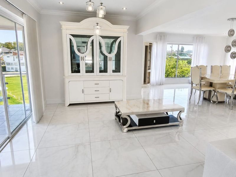 Spacious open-plan living and dining area featuring polished marble-look floor tiles, recessed lighting, and large sliding glass doors leading to an outdoor balcony.