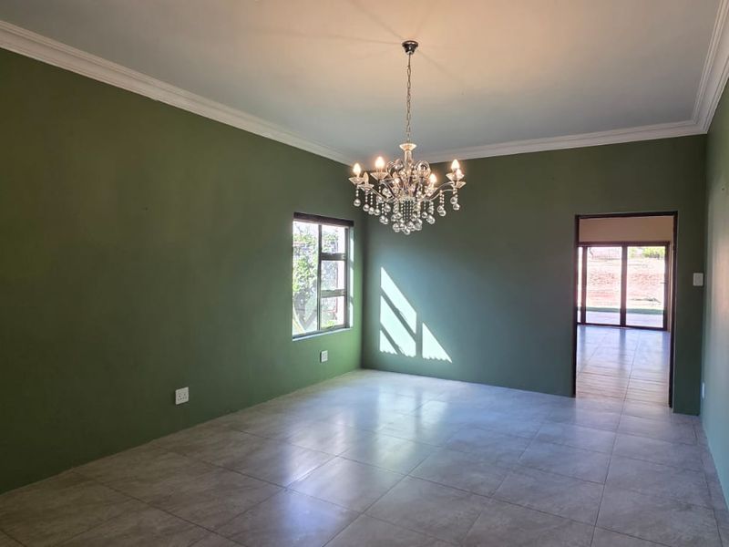 Spacious dining area featuring tiled flooring, crown molding, and an elegant crystal chandelier, with an open flow into the adjacent kitchen and living space.