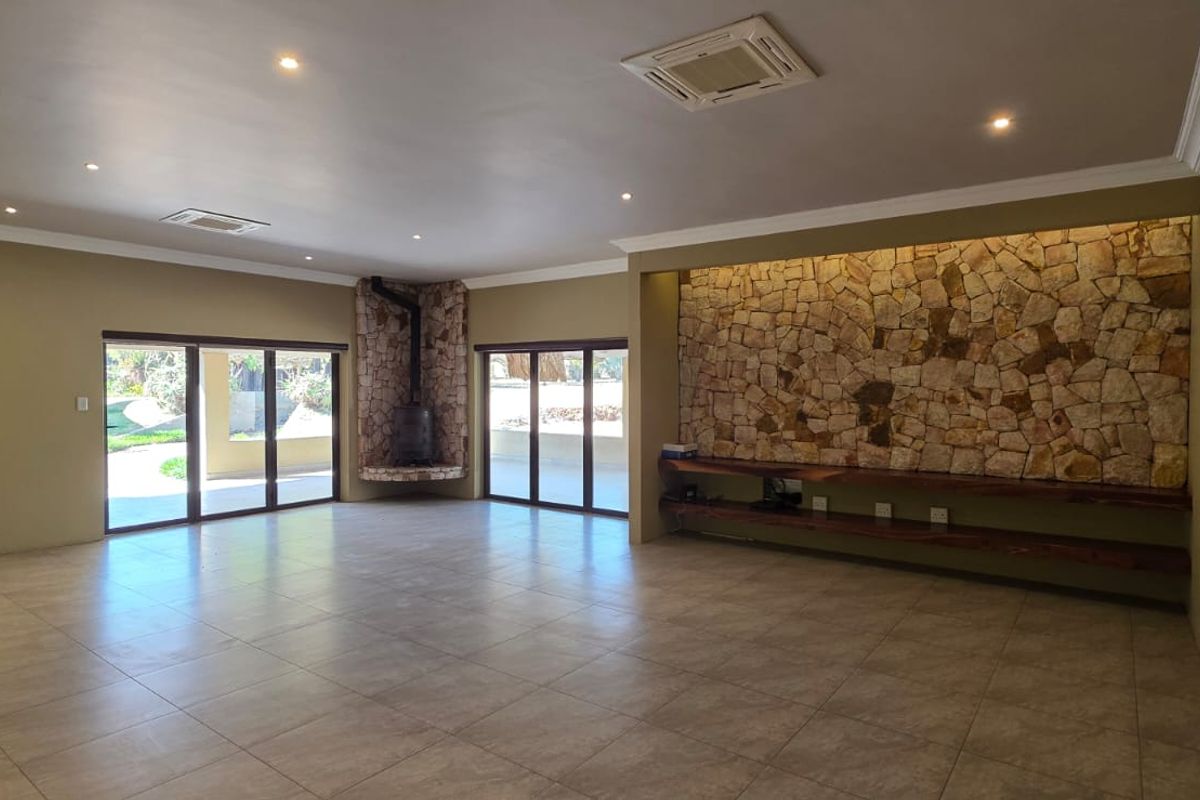 Spacious living area featuring a stone accent wall, built-in fireplace, tiled floors, and large sliding doors providing access to the outdoor space.
