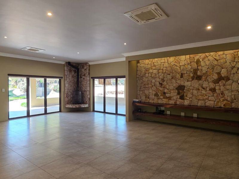 Spacious living area featuring a stone accent wall, built-in fireplace, tiled floors, and large sliding doors providing access to the outdoor space.