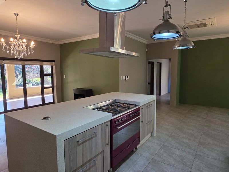 Spacious open-plan kitchen and living area featuring a central island with gas stove, modern cabinetry, and large sliding doors leading to the patio.