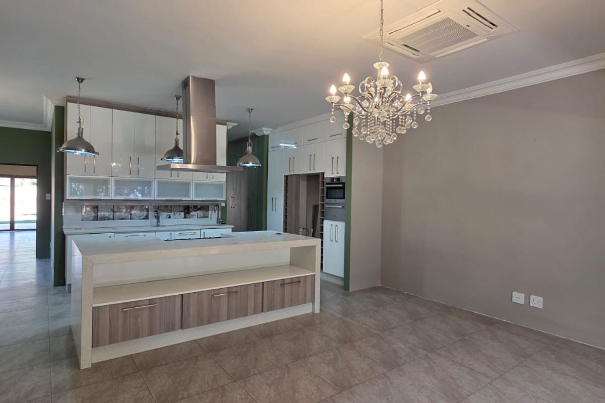 Modern kitchen featuring a central island, sleek built-in cabinetry, integrated appliances, and ducted air conditioning, finished with neutral tones and tiled flooring.