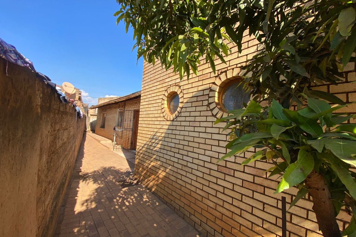 A side walkway featuring face brick walls and distinctive circular windows, leading towards the rear of the property.