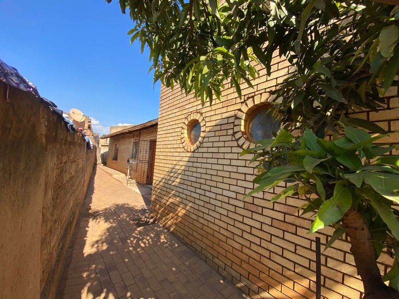 A side walkway featuring face brick walls and distinctive circular windows, leading towards the rear of the property.