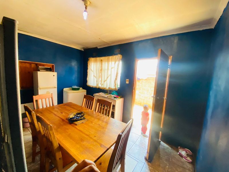 A dining area featuring tiled flooring and direct access to an outdoor space, providing a functional layout with potential for cosmetic updates.