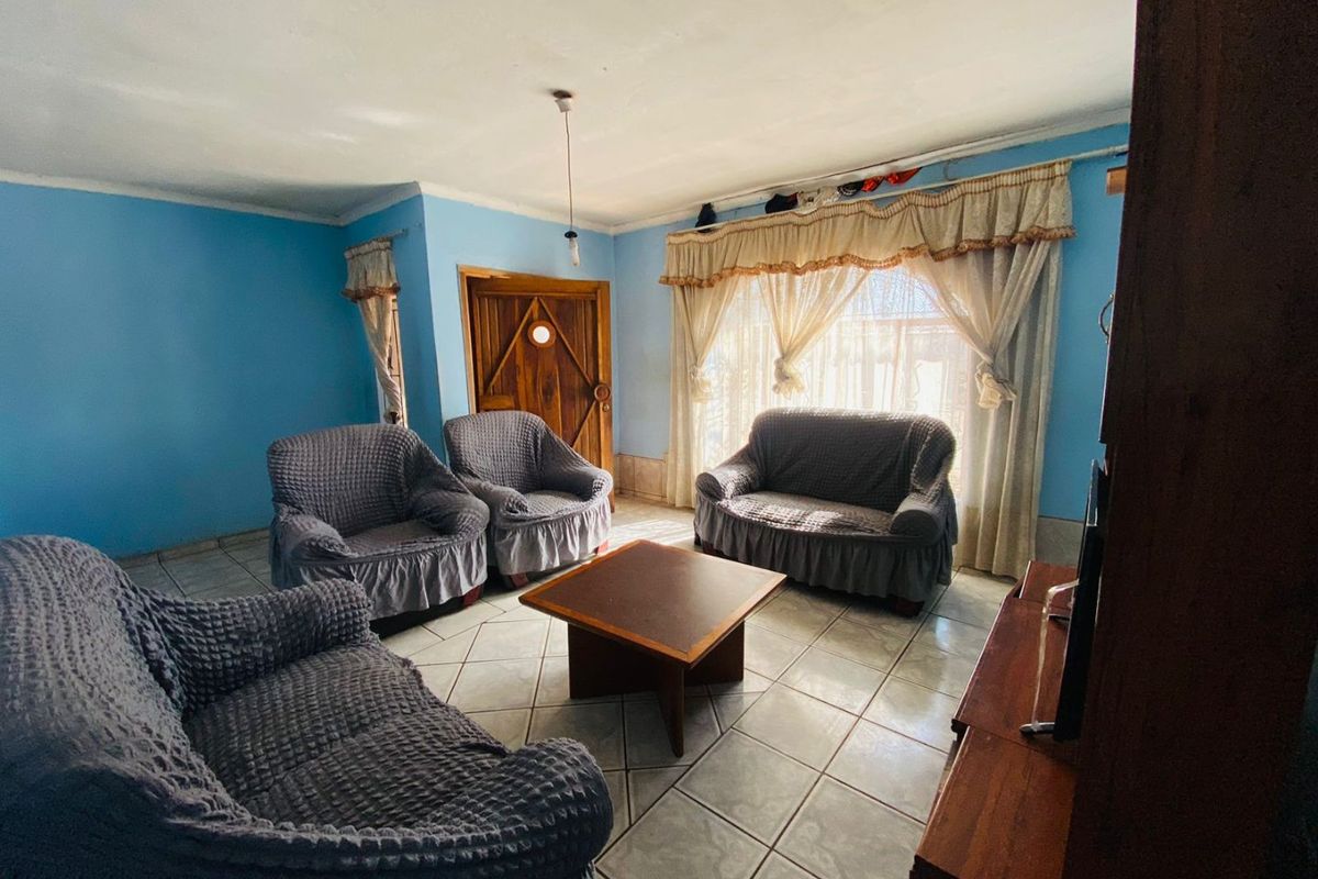 A living room featuring tiled flooring and a timber entrance door, requiring cosmetic updates to improve the overall aesthetic and condition.