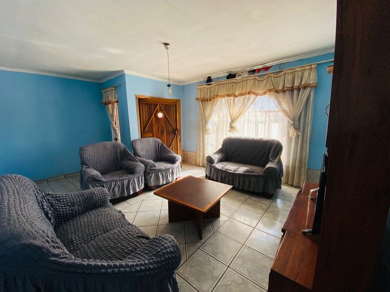 A living room featuring tiled flooring and a timber entrance door, requiring cosmetic updates to improve the overall aesthetic and condition.