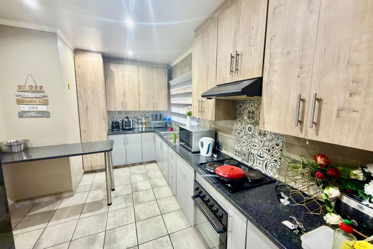 Modern kitchen featuring light wood-grain cabinetry, granite countertops, a built-in oven and stove, decorative backsplash tiling, and a convenient breakfast nook area.