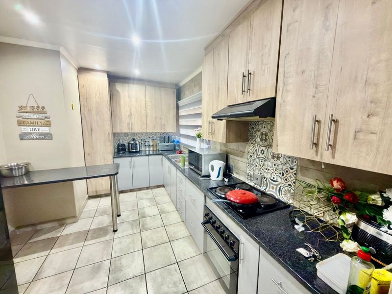 Modern kitchen featuring light wood-grain cabinetry, granite countertops, a built-in oven and stove, decorative backsplash tiling, and a convenient breakfast nook area.