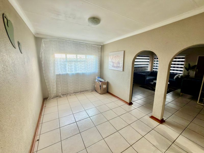 A bright, tiled living area featuring distinctive arched doorways leading to an adjacent space, offering a neutral canvas for interior design.