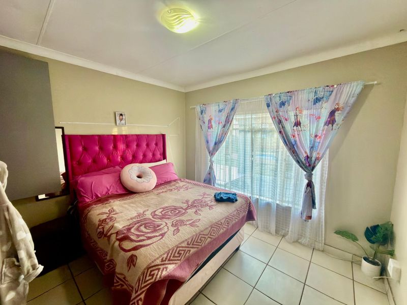 A bedroom featuring tiled flooring, a ceiling light fixture, and a sliding glass door providing natural light.