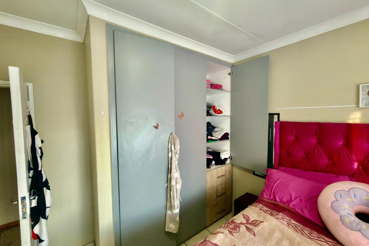 A bedroom featuring a built-in wardrobe with grey doors and cove cornicing, offering functional storage space within the room.