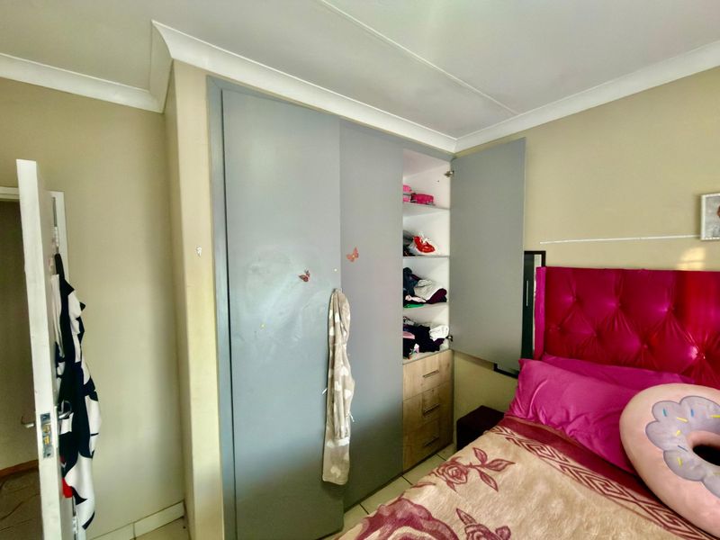 A bedroom featuring a built-in wardrobe with grey doors and cove cornicing, offering functional storage space within the room.