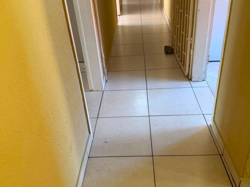 A functional hallway featuring tiled flooring and a security gate, providing access to various rooms within the property.