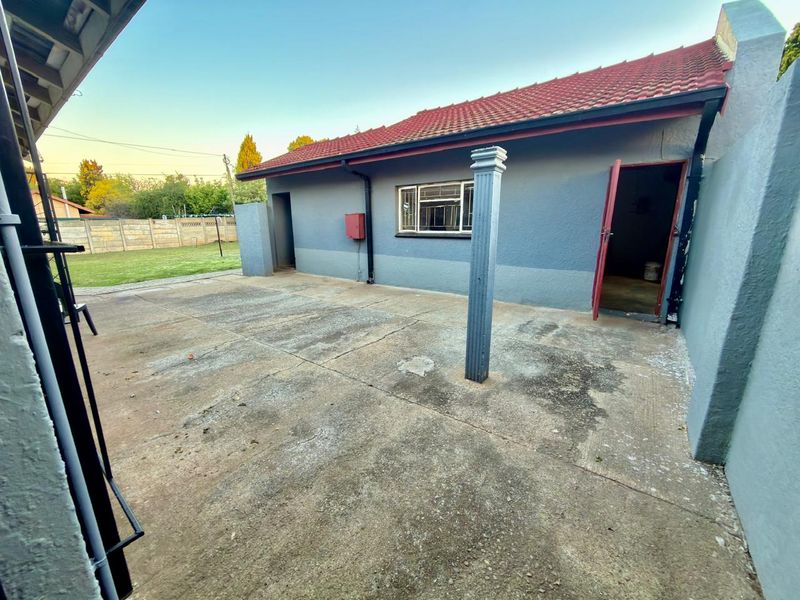 Rear exterior view of the property featuring a concrete patio area, tiled roof, and access to the rear yard.