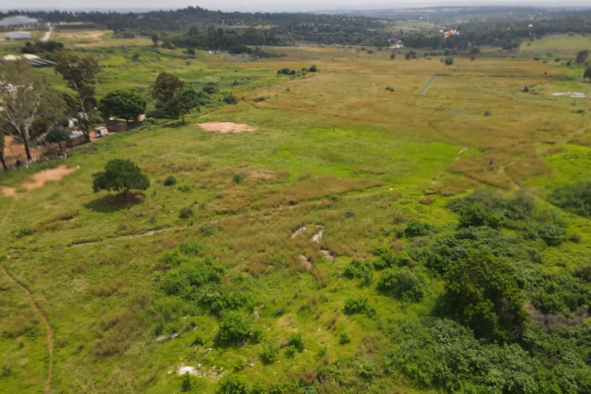 An aerial view of a large, undeveloped residential land plot featuring natural vegetation and surrounding landscape.
