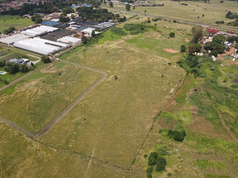 An aerial view of a large, undeveloped residential plot of land featuring open grassland and surrounding rural landscape.