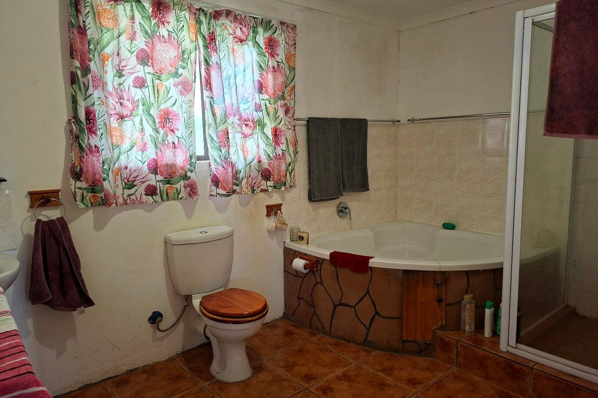 A dated bathroom featuring a corner bathtub, separate shower enclosure, and tiled flooring. The space would benefit from modern updates to finishes and fixtures.
