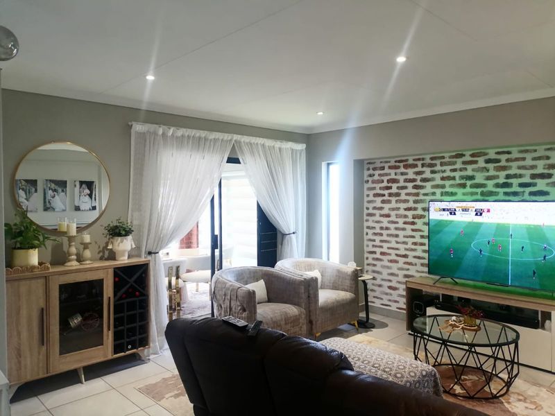 A well-maintained living room featuring an exposed brick accent wall, recessed lighting, and sliding glass doors providing access to the patio area.