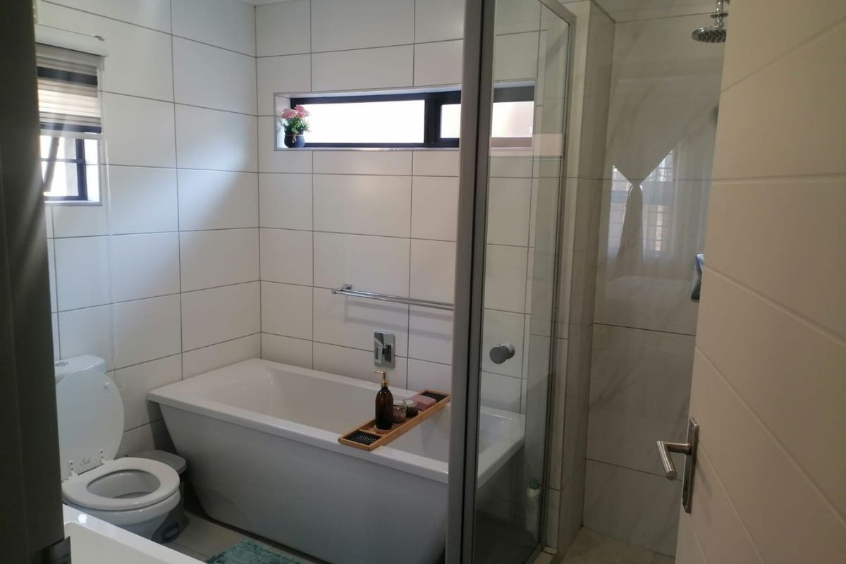 Modern bathroom featuring a freestanding bathtub, a separate glass-enclosed shower, and clean white wall tiling with a functional recessed niche.