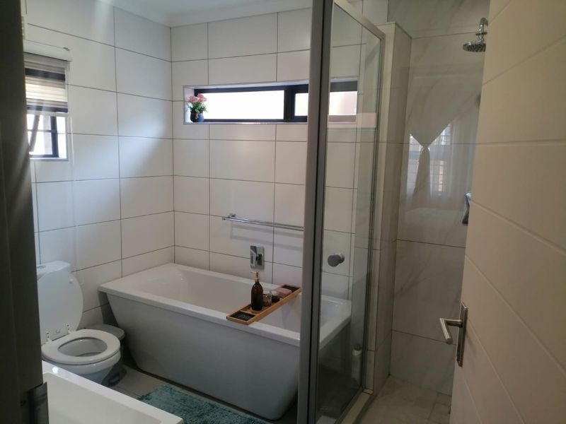 Modern bathroom featuring a freestanding bathtub, a separate glass-enclosed shower, and clean white wall tiling with a functional recessed niche.