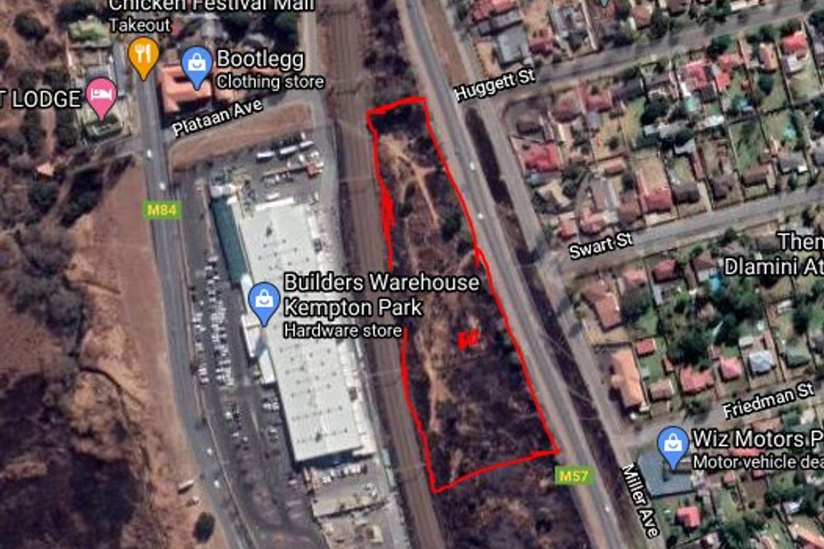 Aerial view of a vacant residential plot situated adjacent to a railway line and commercial infrastructure in Kempton Park.