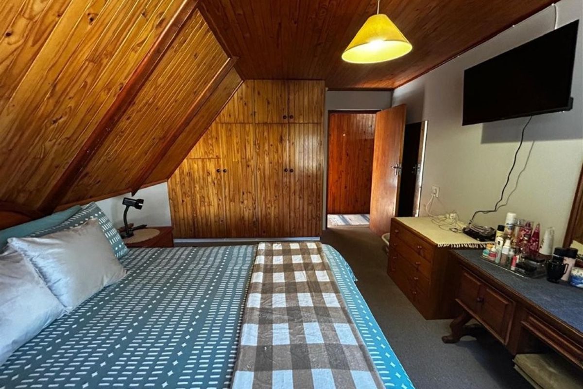 Bedroom featuring a sloped timber-clad ceiling, built-in wooden cabinetry, and carpeted flooring.