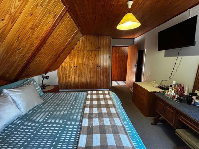 Bedroom featuring a sloped timber-clad ceiling, built-in wooden cabinetry, and carpeted flooring.