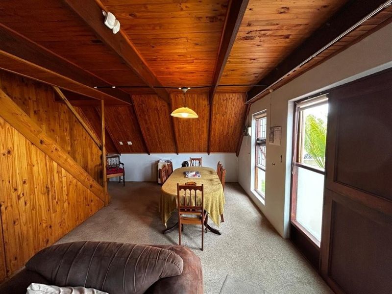 Dining area featuring a distinctive timber-clad vaulted ceiling, wood wall paneling, and direct access to the exterior via a sliding glass door.