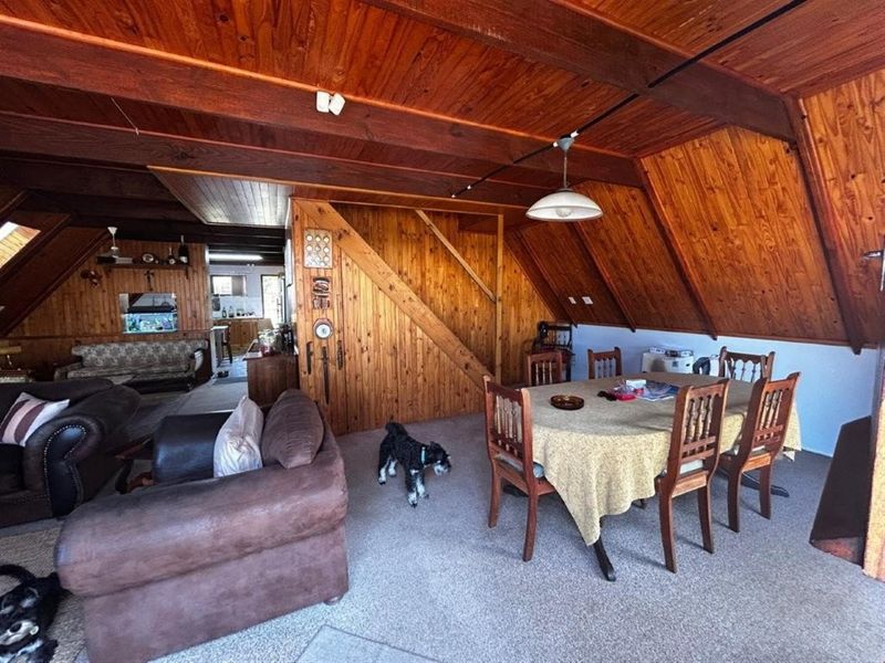 Open plan living and dining area featuring extensive timber paneling on walls and ceilings, creating a rustic and warm atmosphere.