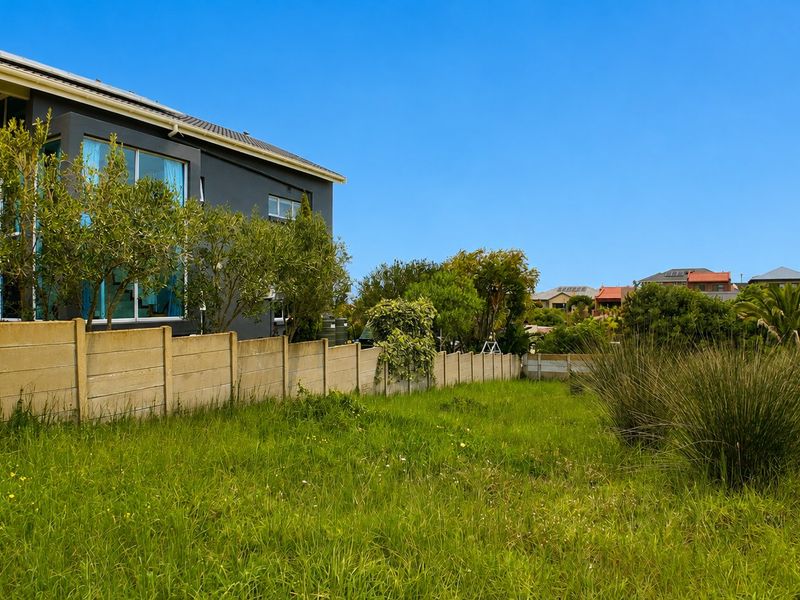 A view of the vacant residential land featuring a precast concrete boundary wall and established grass coverage.