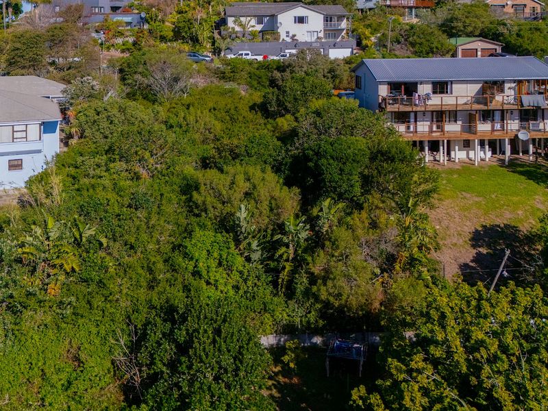 An aerial view of a sloped, heavily vegetated residential vacant land plot situated between existing neighboring properties.
