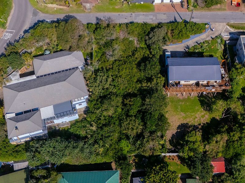 Aerial view of a residential vacant land plot surrounded by established trees and neighboring properties.