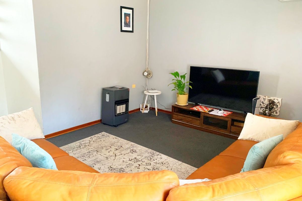 A comfortable living room featuring neutral wall finishes, carpeted flooring, and a wall-mounted air conditioning unit.