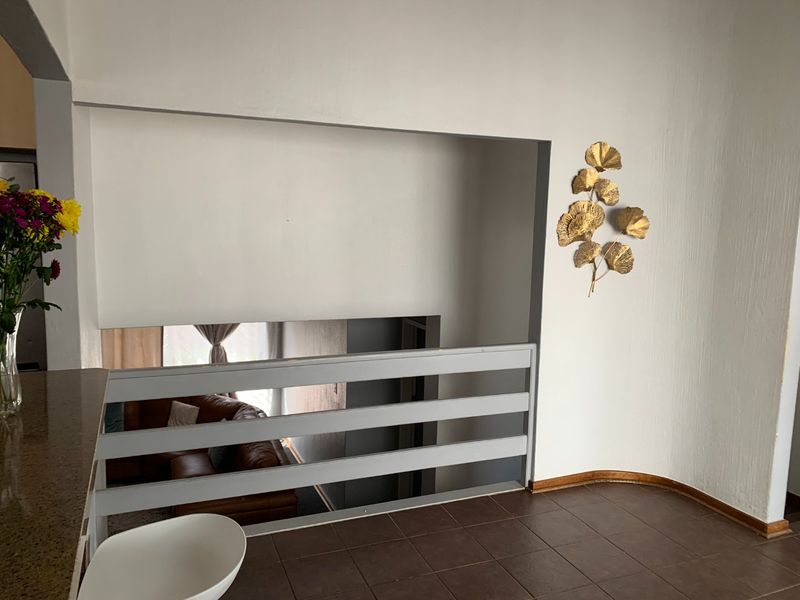 A landing or hallway area featuring tiled flooring and a safety railing overlooking the lower level of the apartment.