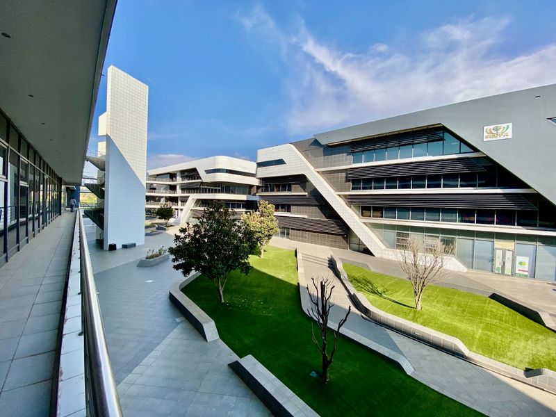A modern commercial office complex featuring contemporary architectural design, glass facades, metal sun-shading louvers, and a well-maintained landscaped courtyard area.