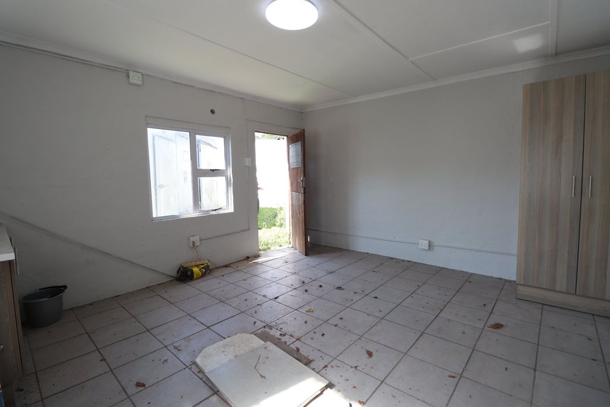An empty living area featuring tiled flooring, a built-in cupboard, and direct access to the exterior.