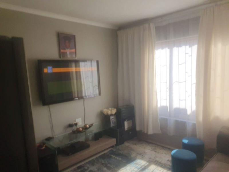 A living room area featuring a window with curtains and wall-mounted television space.