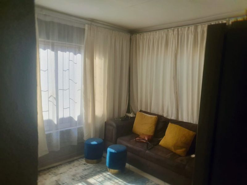 A living room area featuring natural light through windows with security bars and curtain tracks.