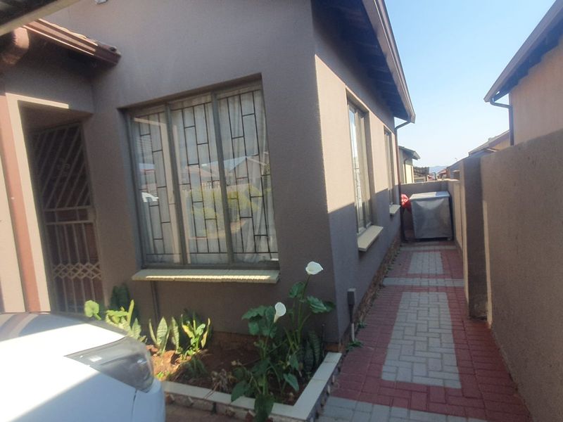 A view of the side exterior of the house featuring a paved walkway, security gate, and security bars on the windows.