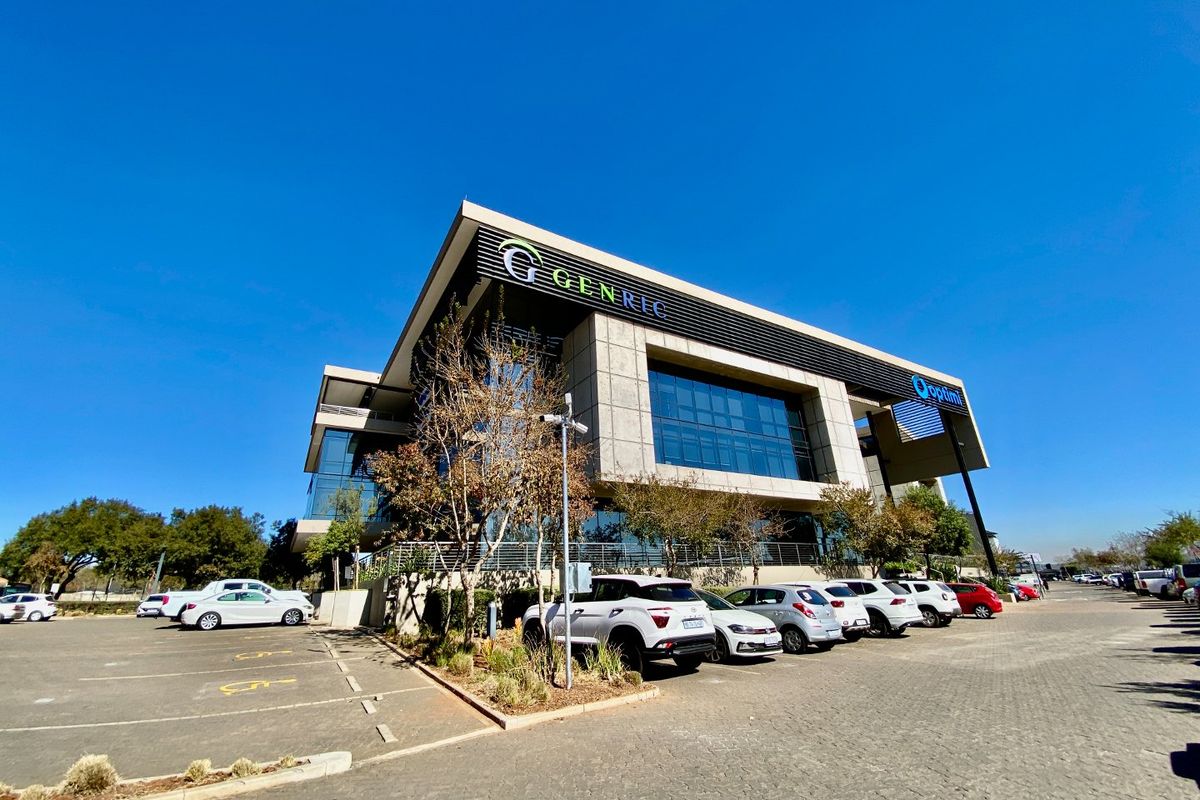 Modern commercial office building featuring a glass and concrete facade with dedicated paved parking and prominent corporate signage.
