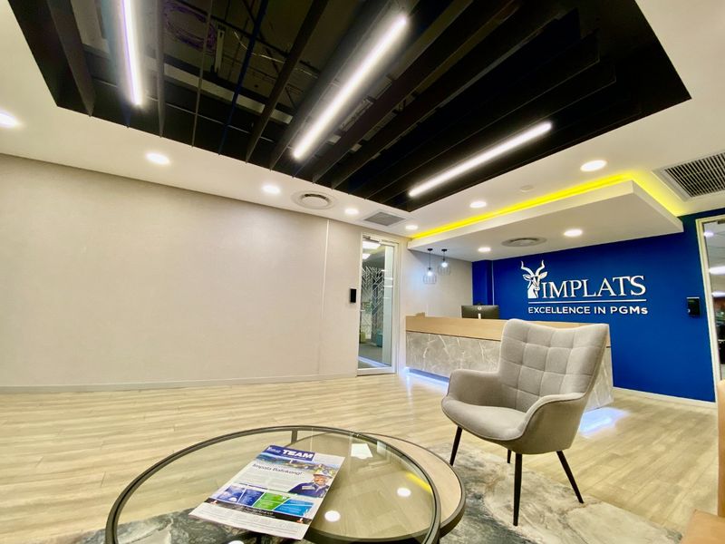 Modern commercial reception area featuring a branded feature wall, sleek reception desk, and contemporary suspended ceiling with integrated lighting.