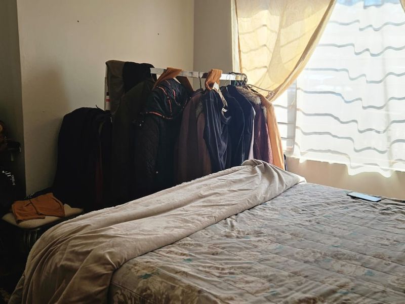 A bedroom featuring a window with natural light and a built-in cupboard, providing a functional space for rest.