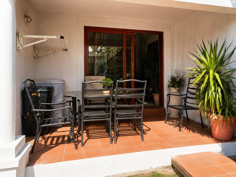 A covered patio area featuring terracotta floor tiles and a sliding glass door entrance to the interior.