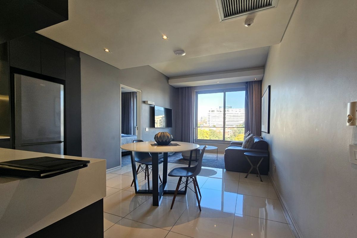 Modern open-plan living and dining area featuring sleek tiled floors, recessed lighting, and large sliding doors leading to a balcony with city views.
