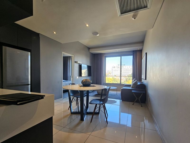 Modern open-plan living and dining area featuring sleek tiled floors, recessed lighting, and large sliding doors leading to a balcony with city views.