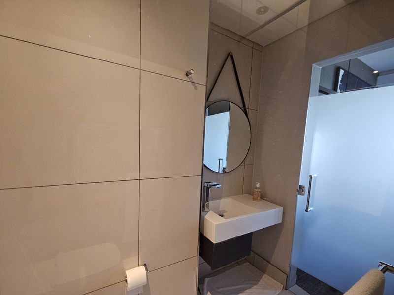 Modern bathroom featuring large format wall tiles, a wall-mounted vanity with basin, and a frosted glass door.